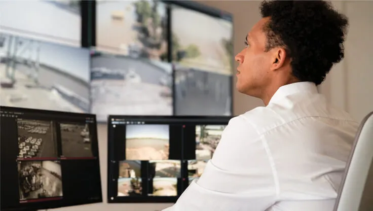 A male looking at CCTV footage from various monitor screens