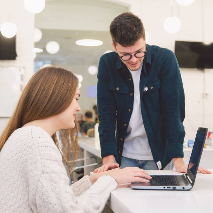 Senior HR team member guiding a new hire through a task