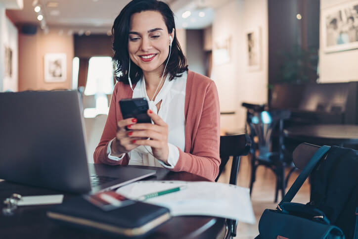 Businesswoman with laptop, smart phone and headphones working in cafe