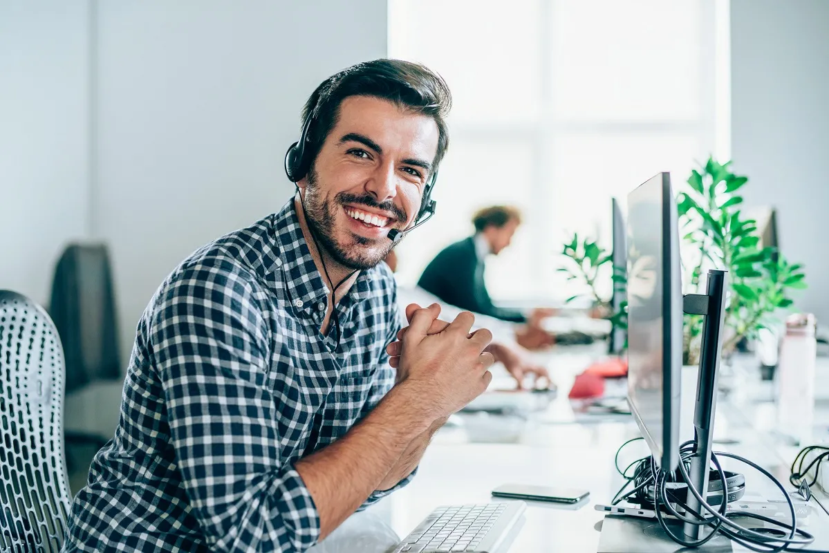 cheerful young man working in a call centre with his team