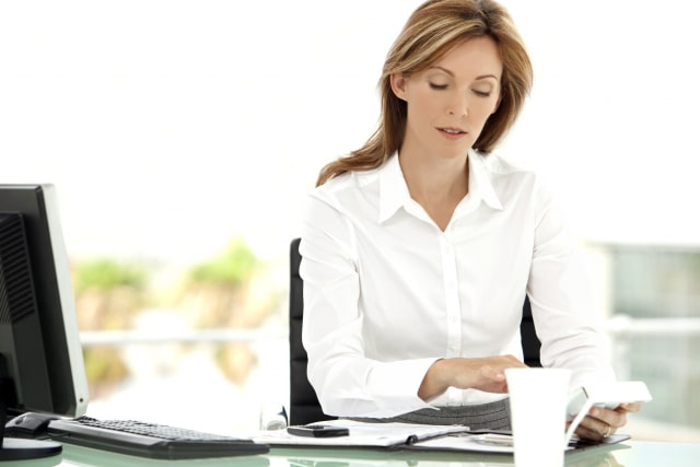 Female CFO sat at her desk in her office reading a report