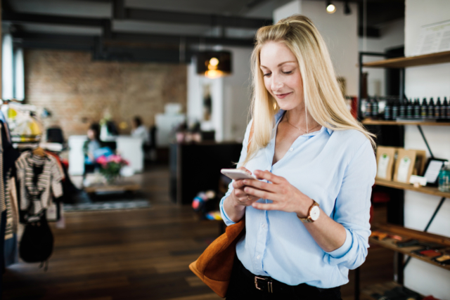 Woman Using SMS on Smartphone While Clothes Shopping