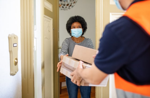 female customer wearing a mask receiving a delivery in the doorway