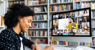 View over shoulder of a mixed race clever female student at a computer screen with a female teacher and students. Teacher conducts online lecture, female student takes notes. Online training,video call-806