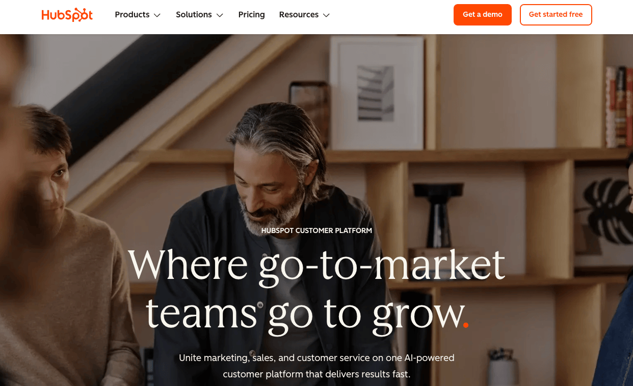 The HubSpot homepage showing people chatting in front of a laptop and the tagline “Where go-to market teams go to grow”